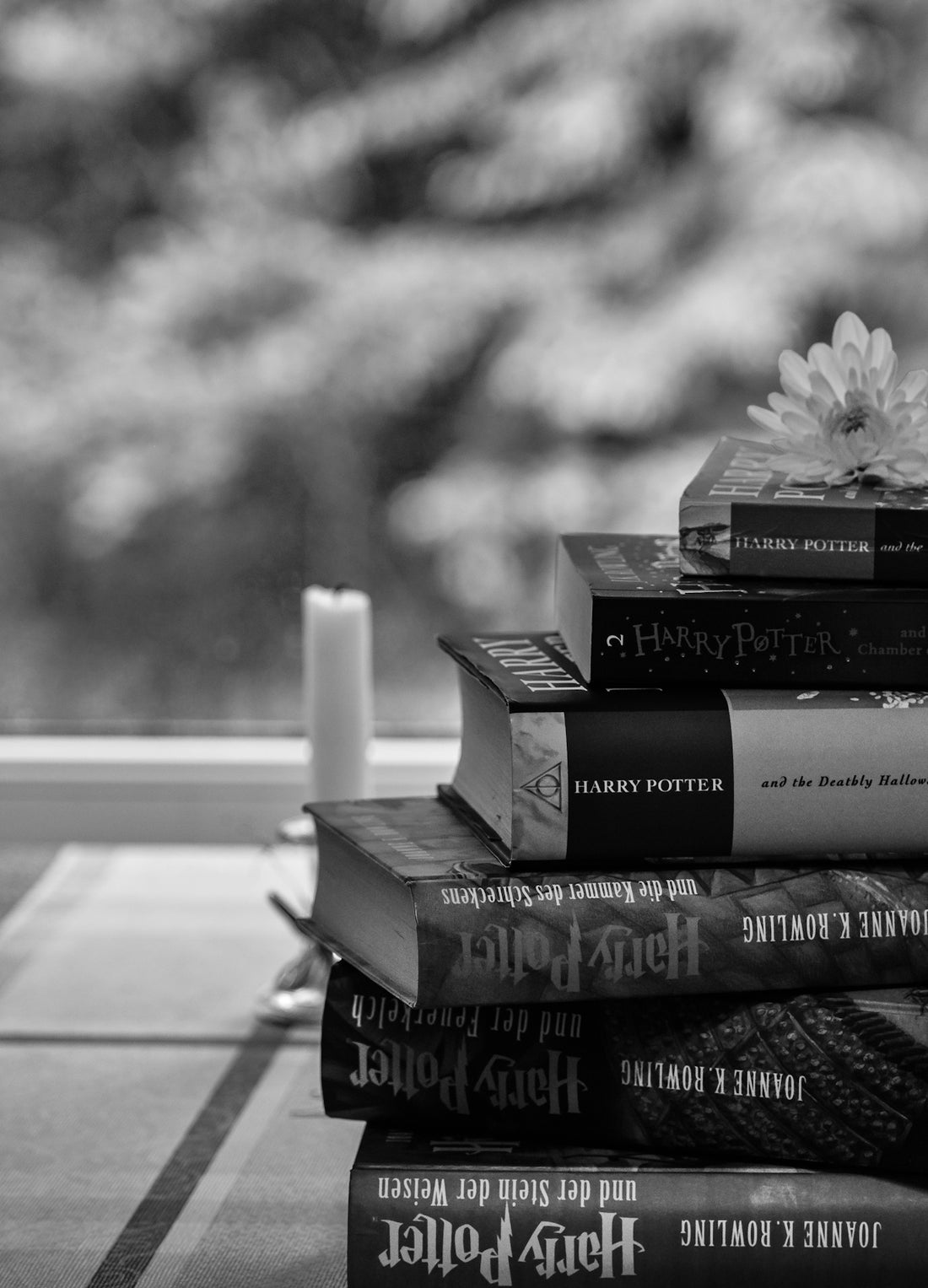 grayscale photo of three books on wooden table