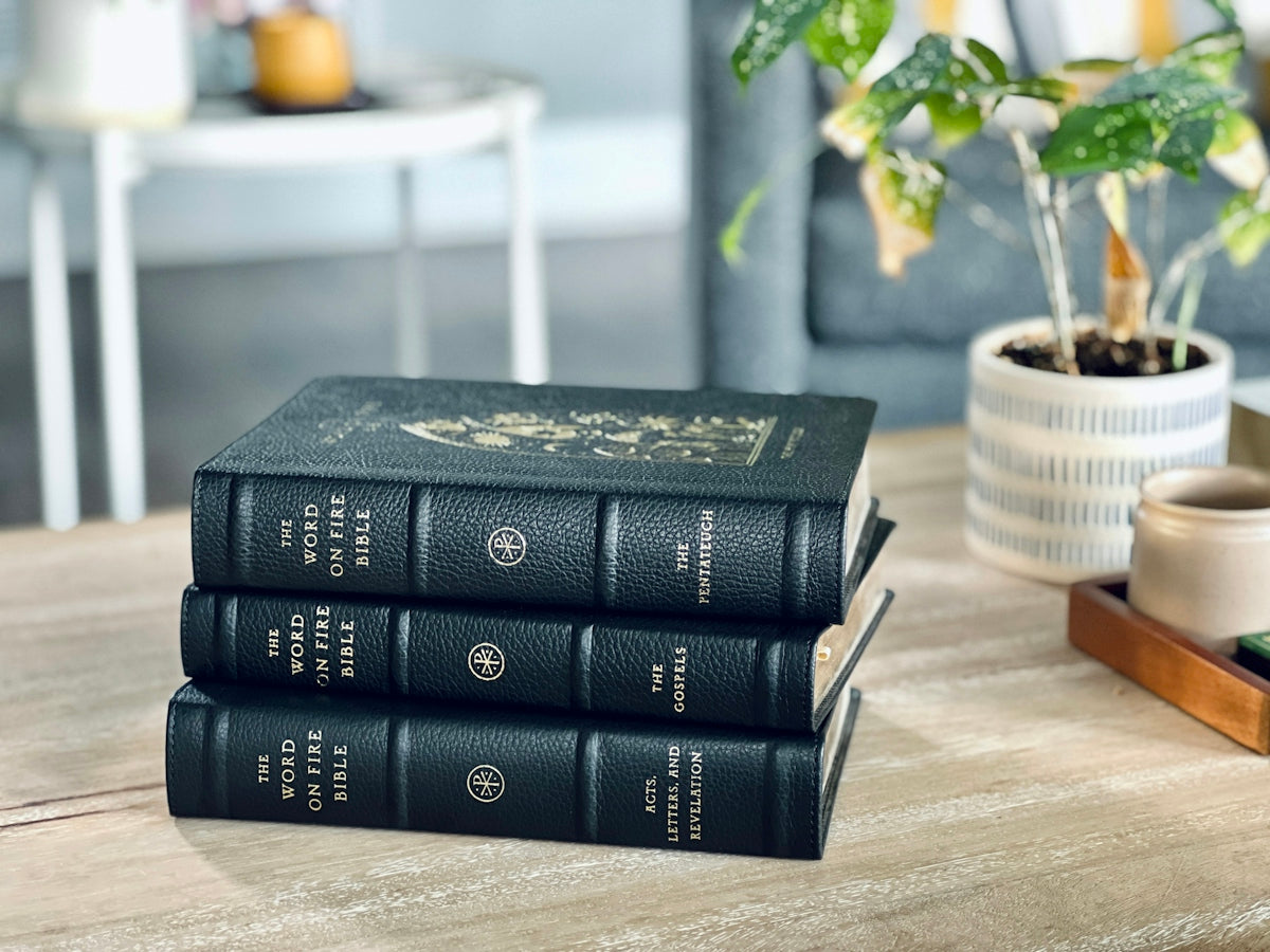 a stack of three books sitting on top of a wooden table