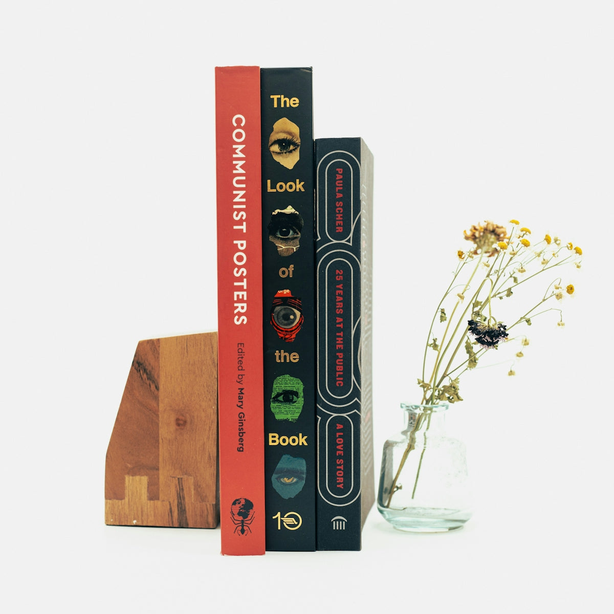 a stack of books sitting next to a vase of flowers
