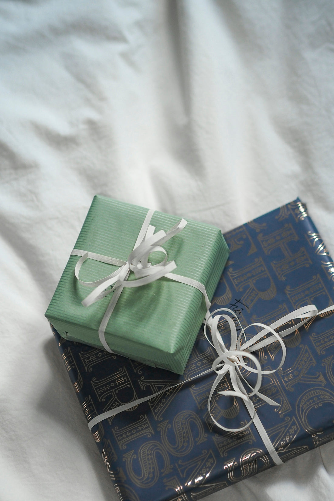Two wrapped presents sitting on top of a bed