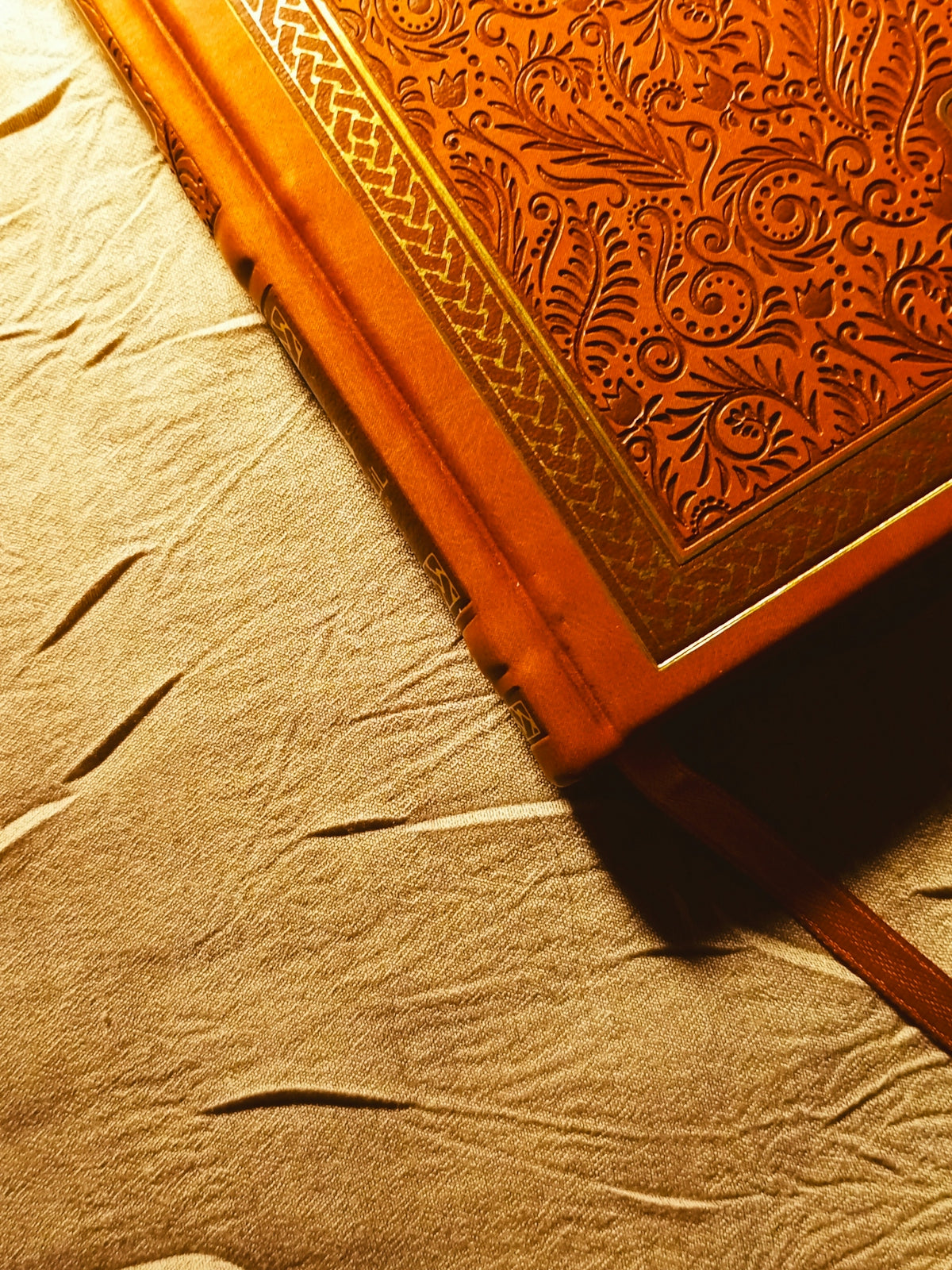 Close-up of an ornate leather-bound book on textured paper