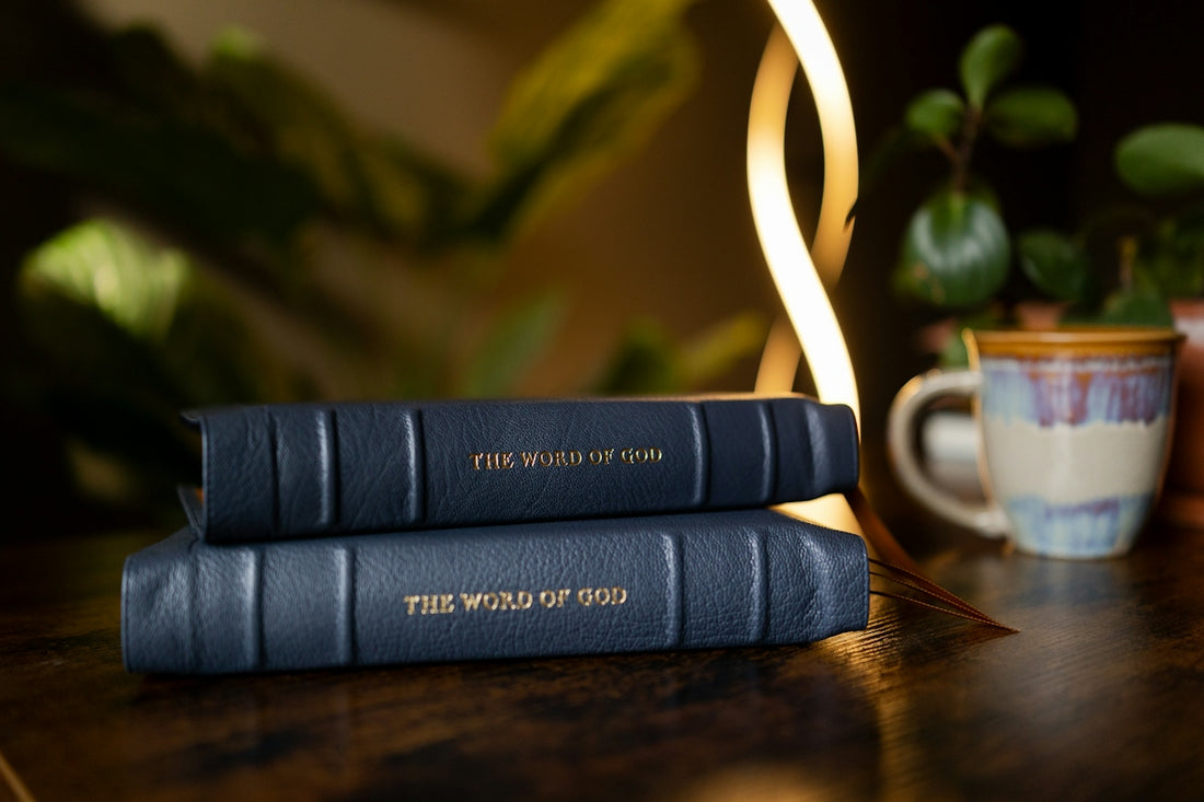 Two dark blue leather books titled THE WORD OF GOD on a wooden table